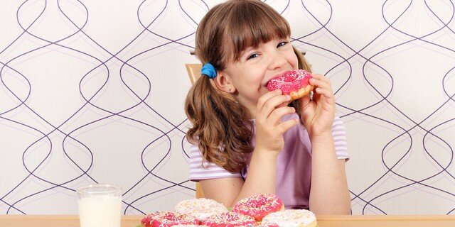 hungry little girl eating sweet donuts